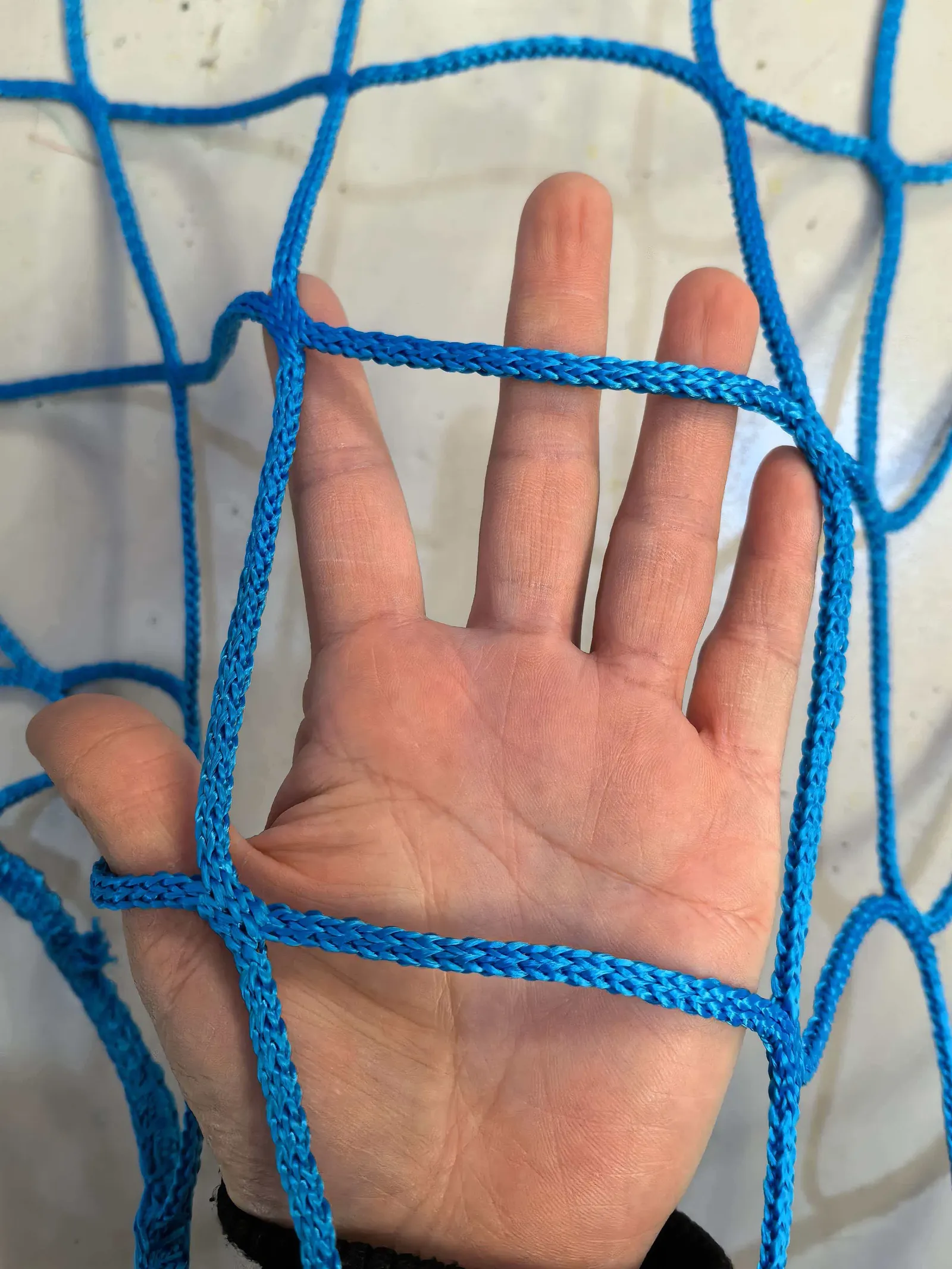 Blue knotless polyester ball stop netting, 100 mm mesh, 5 mm twine, held in hand