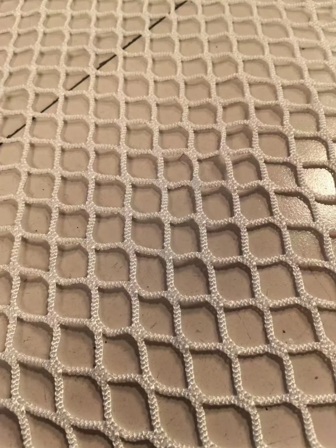 White playground netting, 20 mm mesh, 4 mm twine, factory close-up on tiles