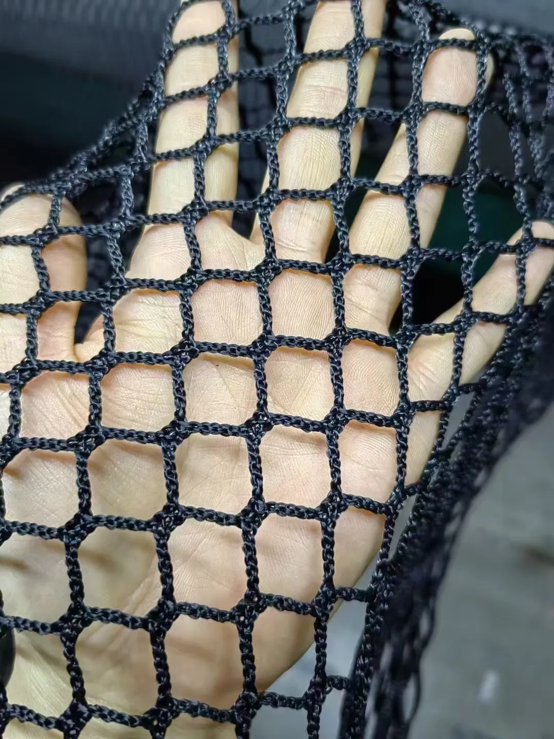 Black polyester netting, 10 mm mesh, 2 mm twine, factory sample held in hand