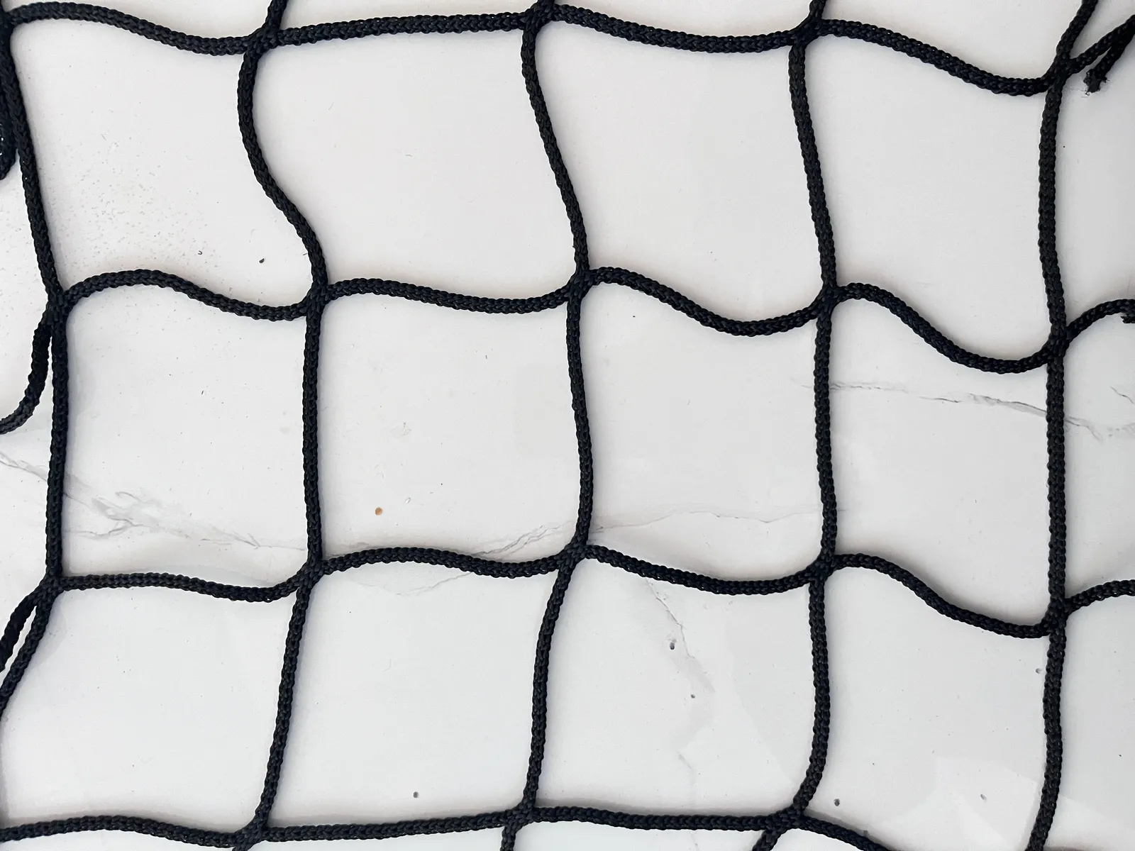 Black polyester netting, 100 mm mesh, 5 mm twine, factory close-up on tiles