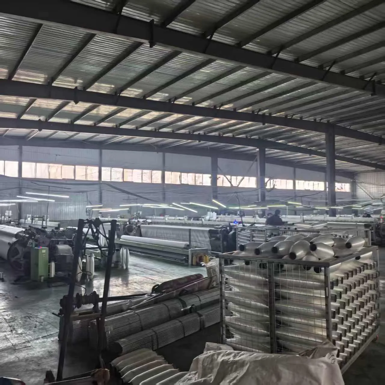 Filas de telares con bobinas de hilo dispuestas al lado en el suelo de la fábrica